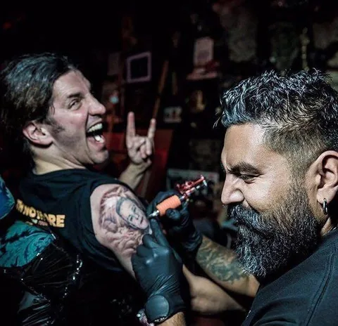 Stefano Alcántara tattooing Frank Bello's arm